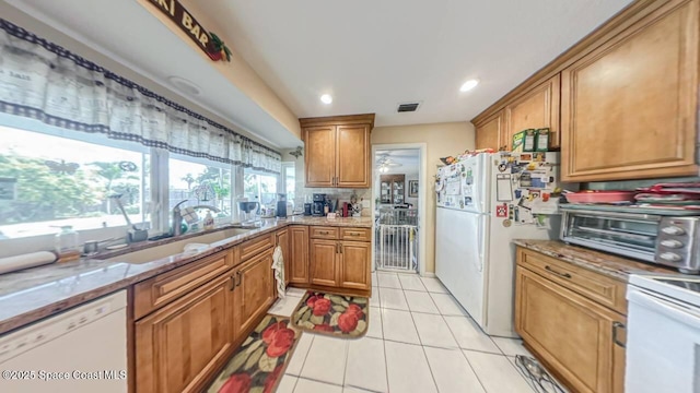699 Bimini Rd, Satellite Beach, FL 32937 - kitchen featuring white appliances, light stone counters, brown cabinetry, light tile patterned floors, and recessed lighting