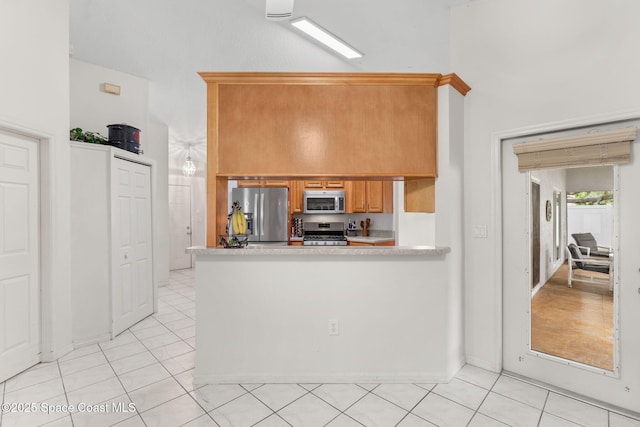 878 Croton Rd, Rockledge, FL 32955 - kitchen featuring appliances with stainless steel finishes, light countertops, light tile patterned floors, a peninsula, and brown cabinets
