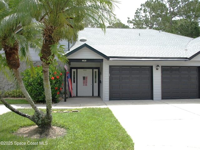 9020 York Ln Unit C, West Melbourne, FL 32904 - view of front facade with driveway, an attached garage, a shingled roof, and a front lawn