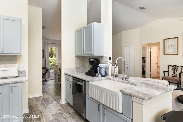 2606 Tepee Ave SE, Palm Bay, FL 32909 - kitchen with stainless steel dishwasher, decorative backsplash, light wood-style flooring, light stone counters, and lofted ceiling