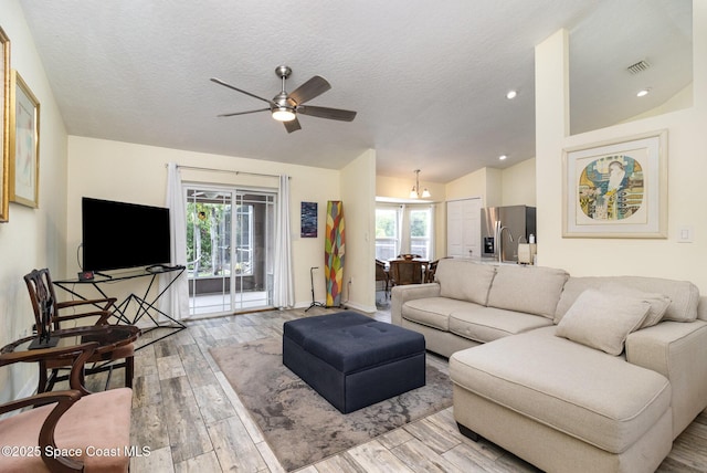 2606 Tepee Ave SE, Palm Bay, FL 32909 - living room featuring wood finished floors, ceiling fan, vaulted ceiling, plenty of natural light, and a chandelier