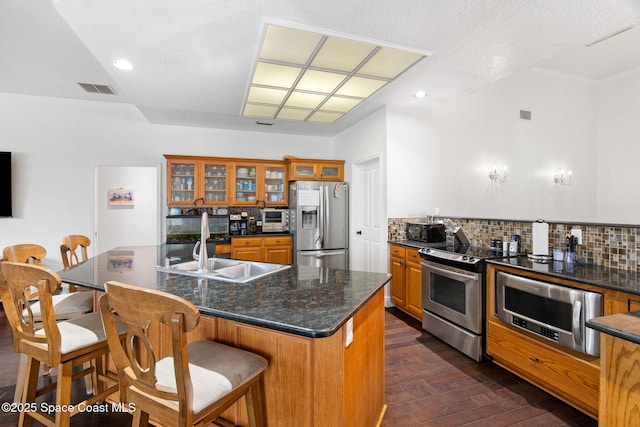 405 Lake View Ln, Grant-Valkaria, FL 32909 - kitchen featuring stainless steel appliances, brown cabinetry, dark wood-style floors, backsplash, and a kitchen breakfast bar