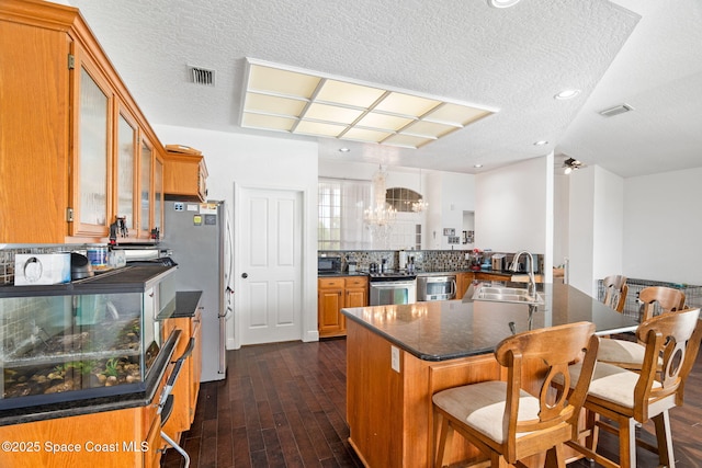 405 Lake View Ln, Grant-Valkaria, FL 32909 - kitchen with a chandelier, appliances with stainless steel finishes, dark wood-style floors, glass insert cabinets, and a textured ceiling