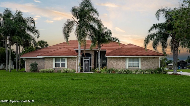 405 Lake View Ln, Grant-Valkaria, FL 32909 - mediterranean / spanish-style home with a tile roof, a lawn, and brick siding