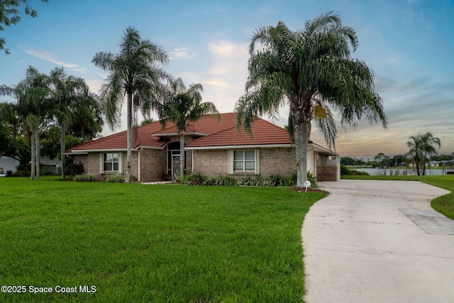405 Lake View Ln, Grant-Valkaria, FL 32909 - view of front of house featuring a tiled roof, concrete driveway, a front yard, and a water view