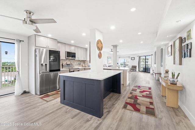 1525 S Atlantic Ave Unit 401, Cocoa Beach, FL 32931 - kitchen featuring appliances with stainless steel finishes, light wood-style flooring, ceiling fan, light countertops, and ornate columns