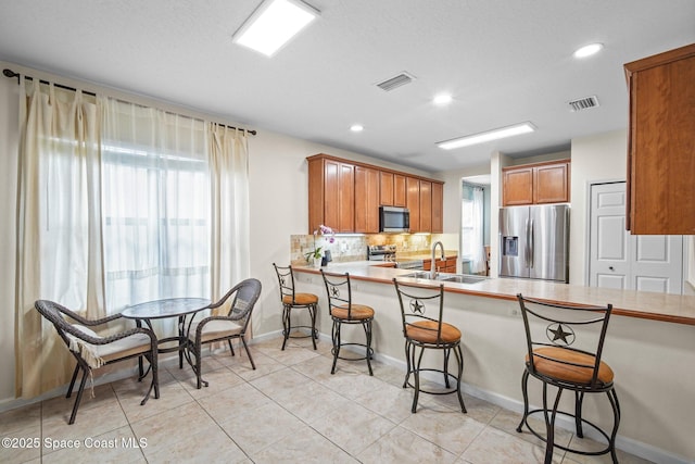 500 Loxley Ct, Titusville, FL 32780 - kitchen featuring appliances with stainless steel finishes, a kitchen breakfast bar, backsplash, brown cabinetry, and recessed lighting