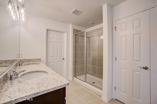 3265 Viridian Cir, West Melbourne, FL 32904 - bathroom with double vanity, tile patterned flooring, a stall shower, and a textured ceiling