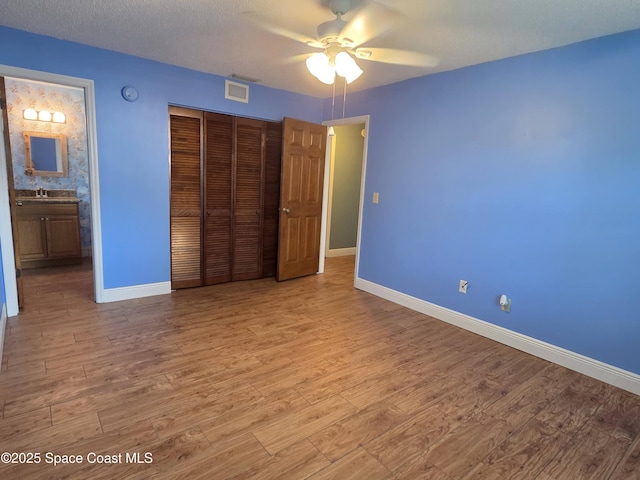 744 John Carroll Ln, Melbourne, FL 32904 - unfurnished bedroom featuring wood finished floors, a closet, ceiling fan, and ensuite bath