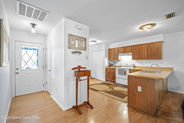 3375 Bryce St, Cocoa, FL 32926 - kitchen with white electric range, light wood finished floors, light countertops, a peninsula, and a textured ceiling