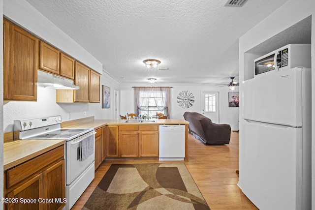 3375 Bryce St, Cocoa, FL 32926 - kitchen with white appliances, a peninsula, light wood finished floors, open floor plan, and a textured ceiling