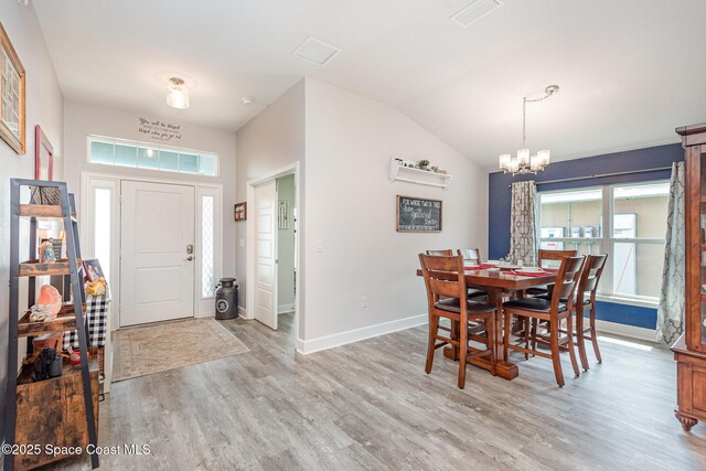 711 Tupelo Cir, Cocoa, FL 32926 - dining room featuring a chandelier, light wood-style flooring, vaulted ceiling, and plenty of natural light