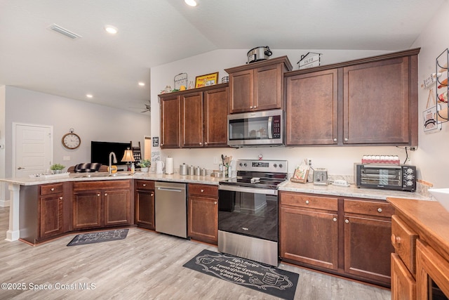 711 Tupelo Cir, Cocoa, FL 32926 - kitchen featuring stainless steel appliances, a peninsula, lofted ceiling, light wood-type flooring, and ceiling fan