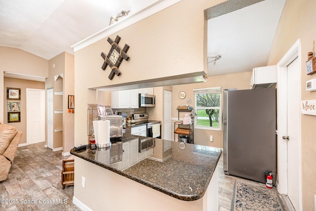 6355 Betty Ave, Cocoa, FL 32927 - kitchen with lofted ceiling, appliances with stainless steel finishes, white cabinets, light wood-style flooring, and a peninsula