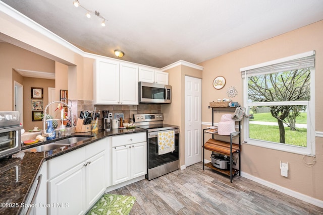 6355 Betty Ave, Cocoa, FL 32927 - kitchen with stainless steel appliances, backsplash, light wood-style floors, dark stone counters, and white cabinetry