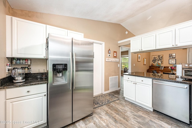 6355 Betty Ave, Cocoa, FL 32927 - kitchen with appliances with stainless steel finishes, vaulted ceiling, white cabinetry, light wood finished floors, and dark stone countertops