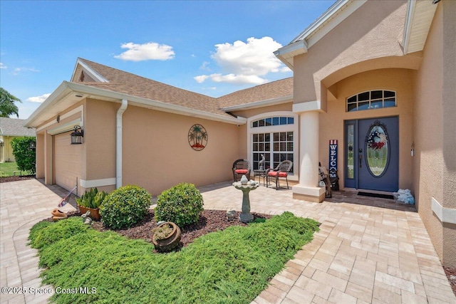 3616 Peninsula Cir, Melbourne, FL 32940 - view of exterior entry featuring stucco siding, a garage, driveway, and roof with shingles