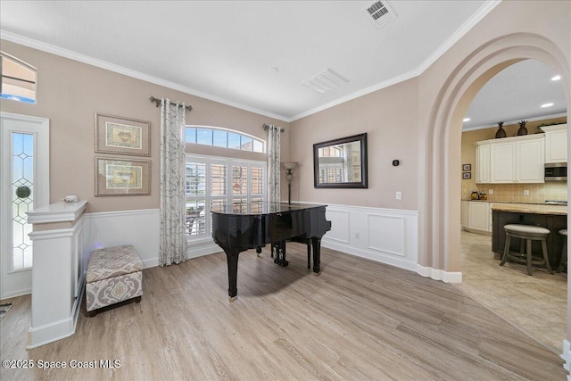 3616 Peninsula Cir, Melbourne, FL 32940 - living area with crown molding, light wood-style flooring, a wainscoted wall, and arched walkways