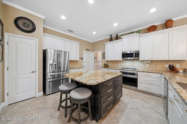 3616 Peninsula Cir, Melbourne, FL 32940 - kitchen with appliances with stainless steel finishes, white cabinetry, a kitchen bar, a center island, and backsplash