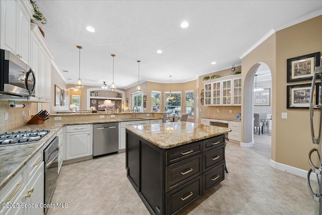 3616 Peninsula Cir, Melbourne, FL 32940 - kitchen featuring appliances with stainless steel finishes, white cabinets, ornamental molding, backsplash, and a peninsula