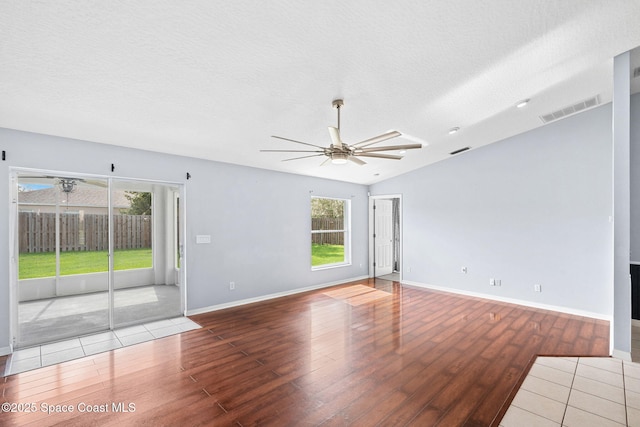 1493 Laramie Cir, Melbourne, FL 32940 - empty room featuring ceiling fan, wood finished floors, healthy amount of natural light, a textured ceiling, and lofted ceiling