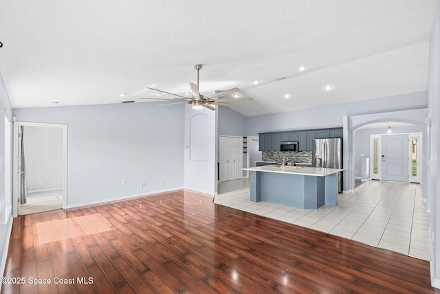 1493 Laramie Cir, Melbourne, FL 32940 - kitchen with vaulted ceiling, stainless steel appliances, light wood-style flooring, arched walkways, and open floor plan