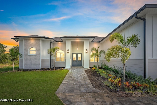 278 Stallion St, Palm Bay, FL 32909 - view of exterior entry with french doors, a yard, and board and batten siding