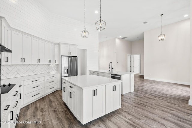 278 Stallion St, Palm Bay, FL 32909 - kitchen featuring stainless steel appliances, a kitchen island, wood finished floors, decorative backsplash, and light countertops