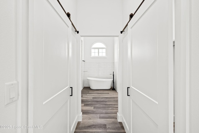 278 Stallion St, Palm Bay, FL 32909 - corridor featuring a barn door, tile walls, dark wood-style flooring, and a wainscoted wall