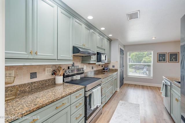 560 Conifer St, Melbourne, FL 32904 - kitchen with appliances with stainless steel finishes, under cabinet range hood, light wood-style flooring, decorative backsplash, and light stone counters