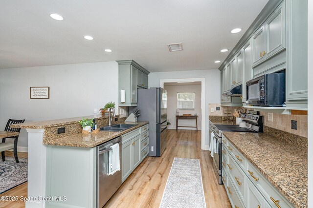 560 Conifer St, Melbourne, FL 32904 - kitchen featuring stainless steel appliances, under cabinet range hood, backsplash, light wood finished floors, and recessed lighting