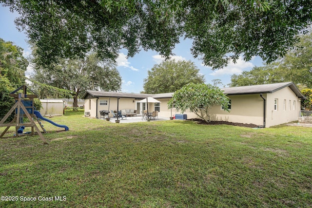 560 Conifer St, Melbourne, FL 32904 - rear view of house with stucco siding, a yard, a patio area, and a playground