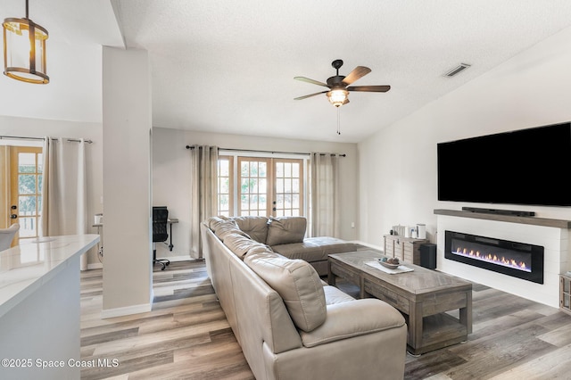 1519 Bronco Dr, Melbourne, FL 32940 - living area with ceiling fan, a glass covered fireplace, light wood finished floors, vaulted ceiling, and french doors