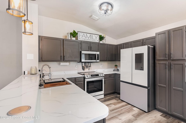 1519 Bronco Dr, Melbourne, FL 32940 - kitchen featuring appliances with stainless steel finishes, lofted ceiling, light wood-type flooring, light stone countertops, and pendant lighting