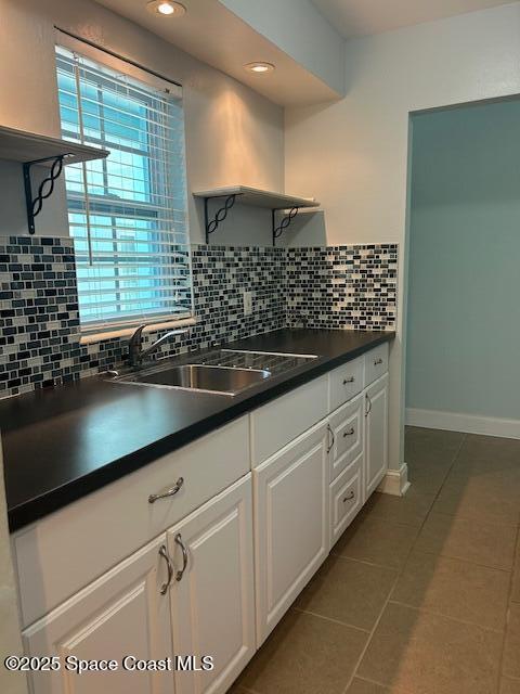 351 Taylor Ave Unit E5, Cape Canaveral, FL 32920 - kitchen featuring open shelves, dark countertops, dark tile patterned floors, backsplash, and white cabinetry