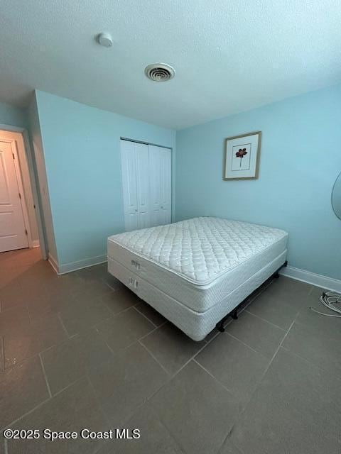 351 Taylor Ave Unit E5, Cape Canaveral, FL 32920 - bedroom with a closet, dark tile patterned flooring, and a textured ceiling