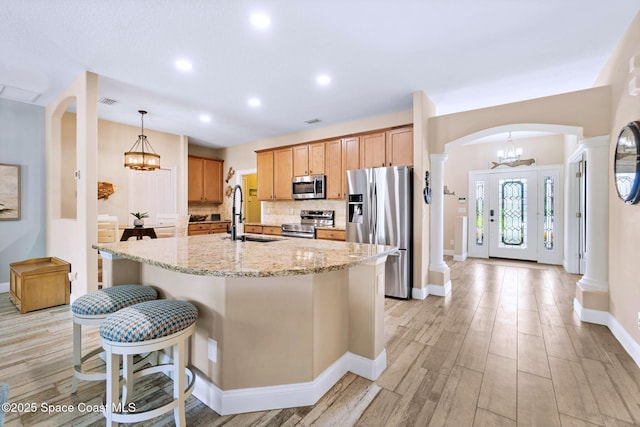 5337 Indigo Crossing Dr, Rockledge, FL 32955 - kitchen with stainless steel appliances, arched walkways, tasteful backsplash, light stone counters, and light wood-style floors