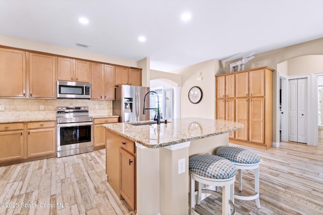 5337 Indigo Crossing Dr, Rockledge, FL 32955 - kitchen featuring stainless steel appliances, arched walkways, an island with sink, light wood finished floors, and recessed lighting