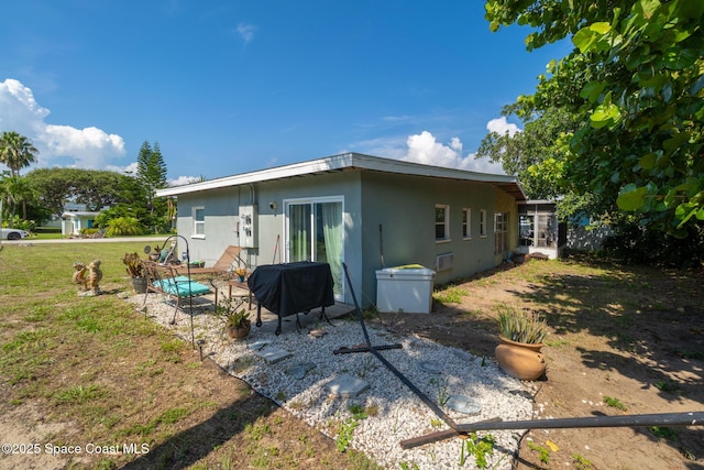 113 Surf Dr, Cocoa Beach, FL 32931 - back of house with a patio, a lawn, and stucco siding
