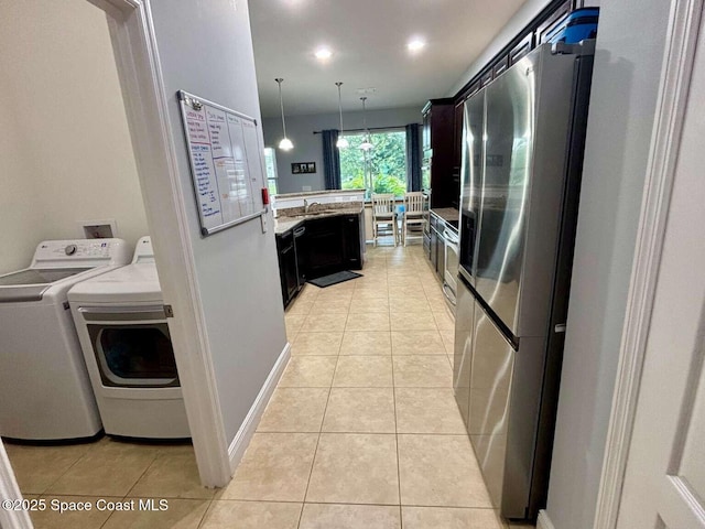 3725 Aria Dr, Melbourne, FL 32904 - kitchen with freestanding refrigerator, light tile patterned floors, washing machine and dryer, dark cabinetry, and hanging light fixtures