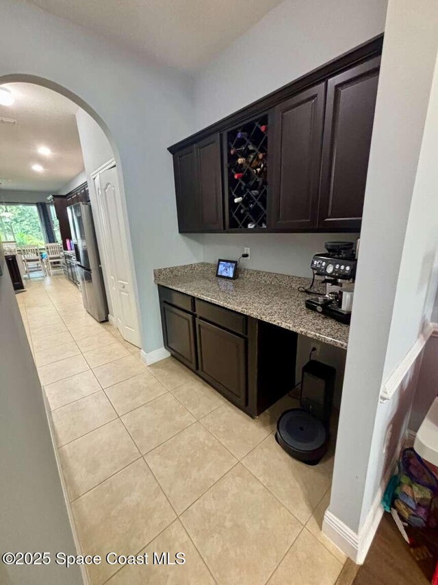 3725 Aria Dr, Melbourne, FL 32904 - bar area with freestanding refrigerator, arched walkways, and light tile patterned flooring