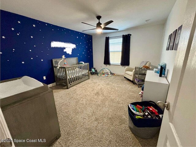 3725 Aria Dr, Melbourne, FL 32904 - bedroom with a crib, an accent wall, carpet flooring, ceiling fan, and wallpapered walls