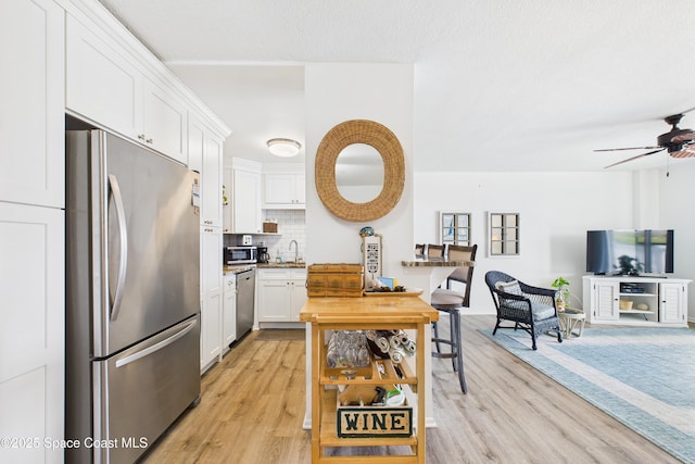 3190 N Atlantic Ave Unit 220, Cocoa Beach, FL 32931 - kitchen with stainless steel appliances, light wood-style floors, white cabinetry, and a ceiling fan