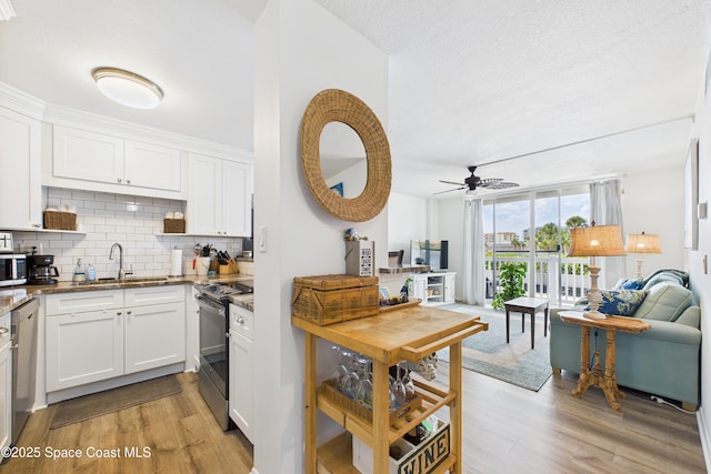 3190 N Atlantic Ave Unit 220, Cocoa Beach, FL 32931 - kitchen with stainless steel appliances, stone countertops, tasteful backsplash, light wood finished floors, and ceiling fan
