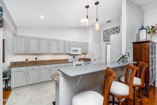 1453 Goldrush Ave, Melbourne, FL 32940 - kitchen with white appliances, a peninsula, a kitchen bar, gray cabinetry, and high vaulted ceiling