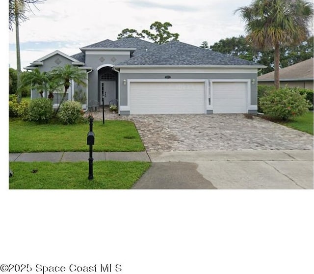3885 Waterford Dr, Rockledge, FL 32955 - view of front of house featuring decorative driveway, a front lawn, stucco siding, and a garage