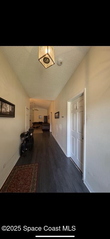 4094 Wilkes Dr, Melbourne, FL 32901 - hallway featuring lofted ceiling, wood finished floors, and a textured ceiling