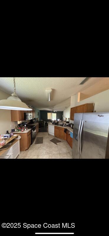 4094 Wilkes Dr, Melbourne, FL 32901 - kitchen featuring appliances with stainless steel finishes, brown cabinets, and light tile patterned flooring