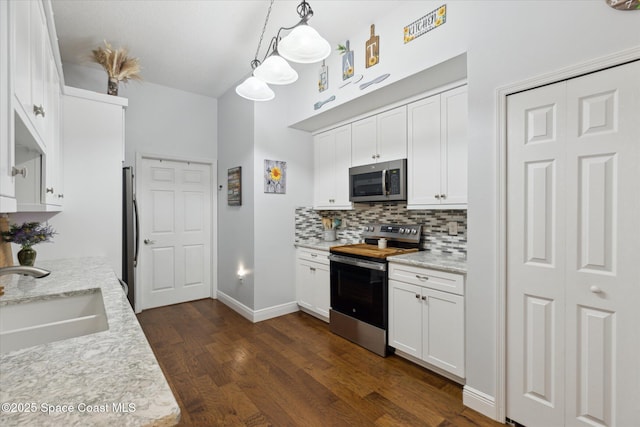 4107 Meander Pl Unit 104, Rockledge, FL 32955 - kitchen with appliances with stainless steel finishes, decorative backsplash, white cabinetry, dark wood finished floors, and hanging light fixtures