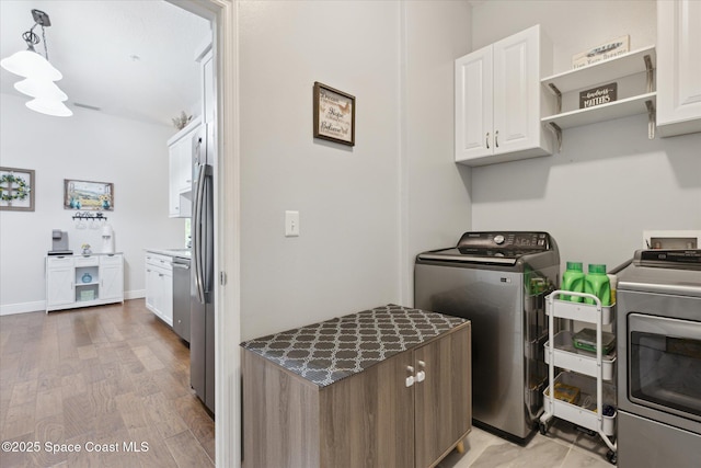 4107 Meander Pl Unit 104, Rockledge, FL 32955 - washroom with washing machine and dryer, cabinet space, and light wood finished floors